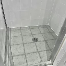 A shower wall and floor tiles after regrouting.