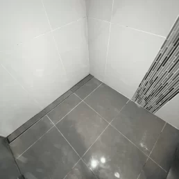 A modern shower in need of regrouting as old grout is falling apart and moldy.