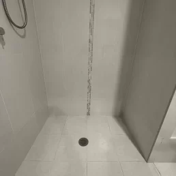 Photo of shower tiles that need new grout as existing grout is cracked and dirty.