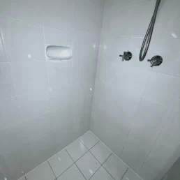 White floor and wall tiles in shower in desperate need of new grout.